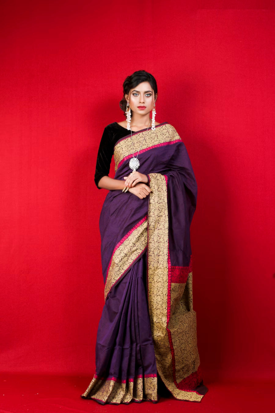 Woman wearing a purple and gold traditional Indian saree with red border.