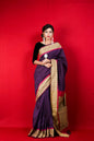 Woman wearing a purple and gold traditional Indian saree with red border.